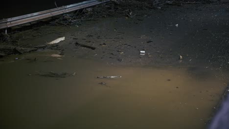 flood debris and pollution in urban river at night