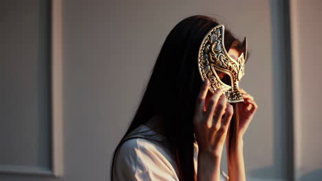 woman adjusting an ornate golden mask