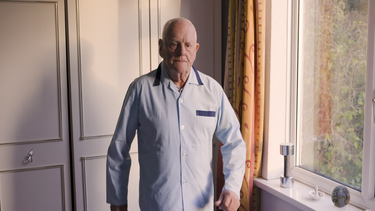 Elderly man exercising with weights in bedroom