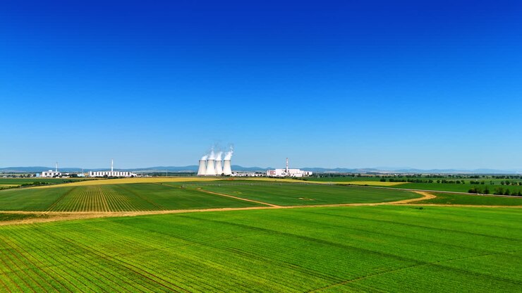 Vasti campi verdi nella campagna della Slovacchia. Stabilimento industriale emette fumo bianco sullo sfondo.