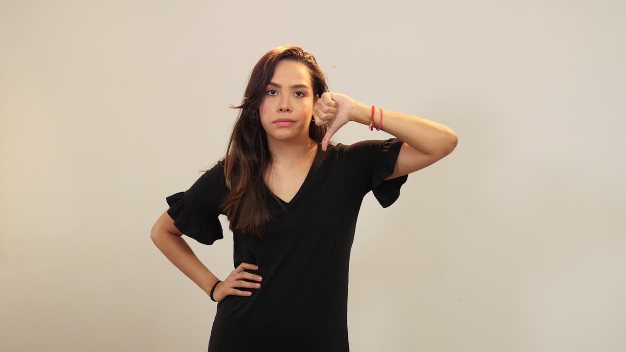 Mujer joven haciendo un signo negativo con el pulgar hacia abajo