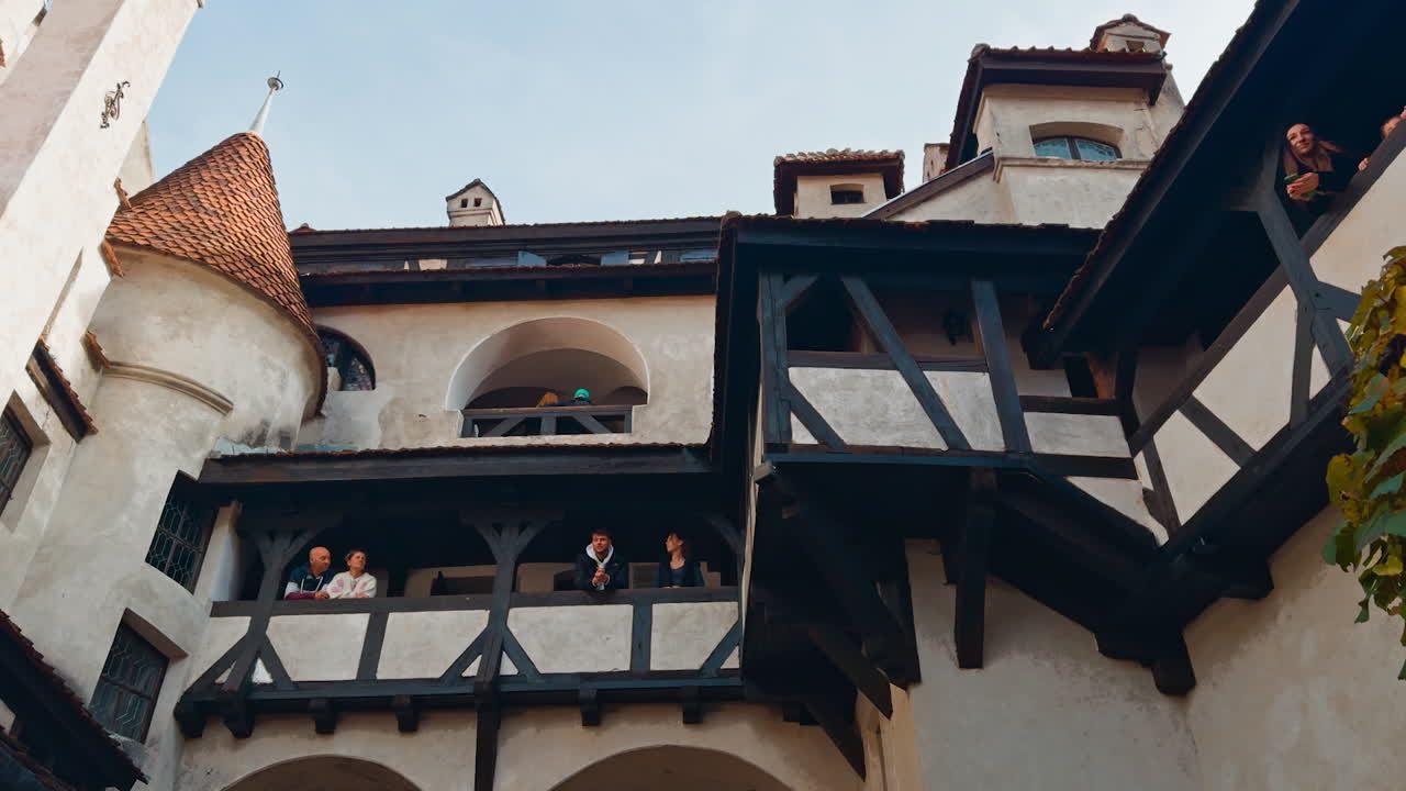 Inner yard in the old medieval castle. Tourists stand on the balconies of the Bran Castle, Brasov, Romania. Low angle view.
