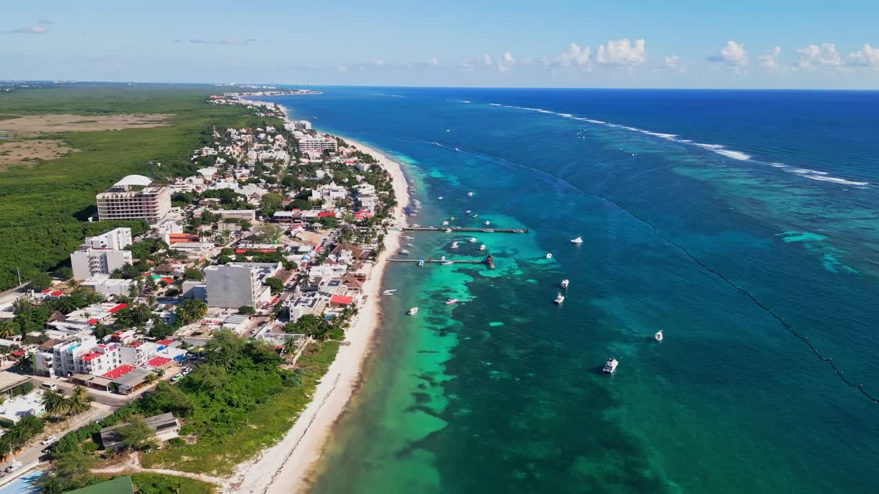 Aerial view of Puerto Morelos, Mexico, showing turquoise Caribbean waters, boats, beaches and the coastline stretching toward the Riviera Maya on a clear sunny day