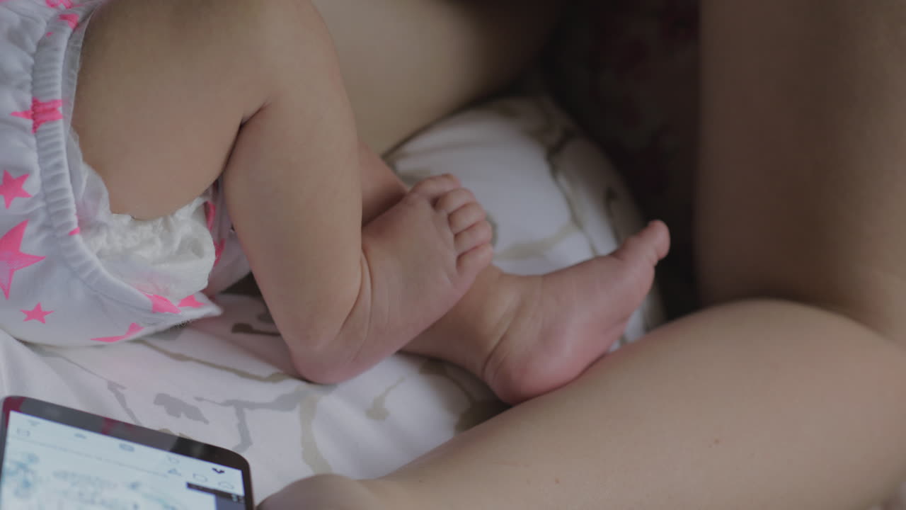 Donna che allatta un bambino e naviga in internet sul cellulare
