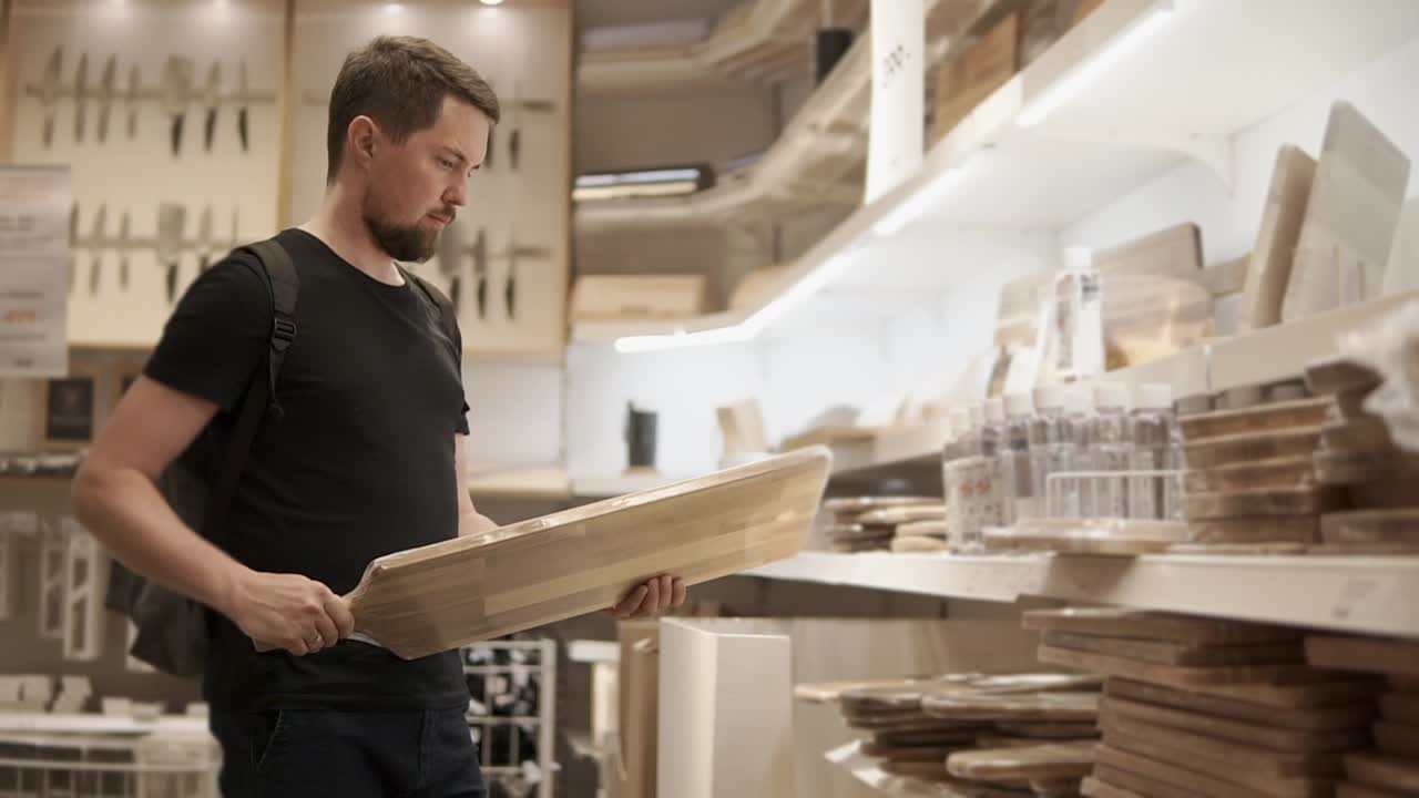 hombre comprando una tabla de cortar de madera en una tienda de muebles