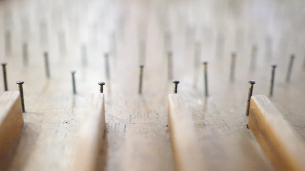 나무로 만든 핀볼 테이블 위에서 유리 구슬이 핀볼테이블 위로 굴러 내려온다.