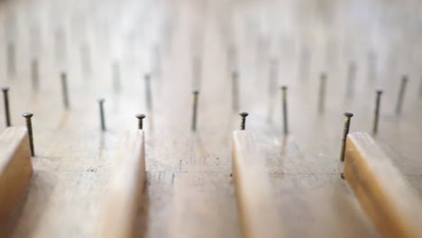 close up on pinball table made of wood. the glass beads roll down on the pinball table. a game played by a child.