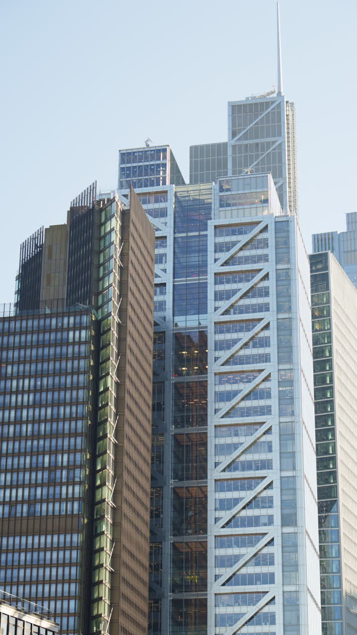 Modern glass skyscrapers of London's financial district reflecting the blue sky next to historic architecture. Vertical