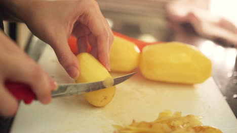 manos femeninas pelando patatas en la cocina a cámara lenta