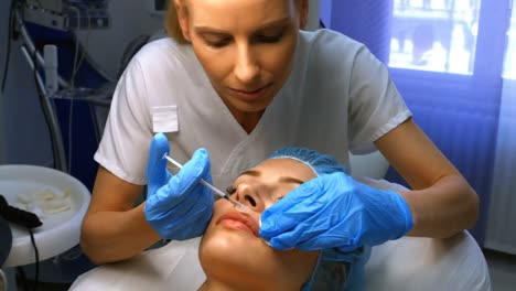 doctor inserting facial injection on female patient lips