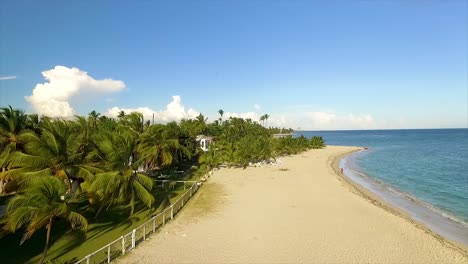 Approaching-drone-shot-slightly-moving-to-the-right-to-show-the-fenced-houses-in-Miami-Beach,-facing-the-crystal-clear-blue-waters-of-the-Mediterranean-Sea,-located-in-the-islands-of-Greece