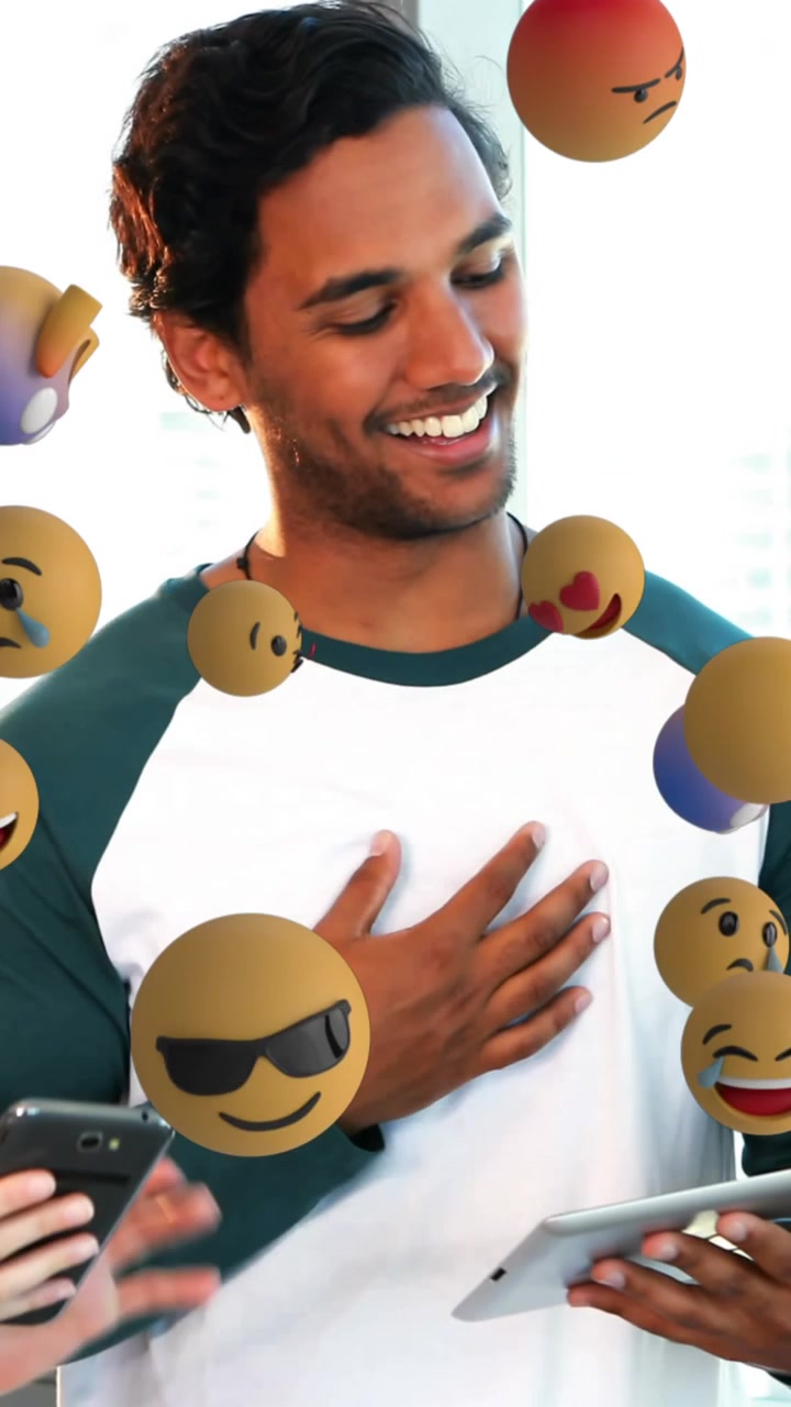 Multiple face emojis floating against office colleagues discussing over digital tablet