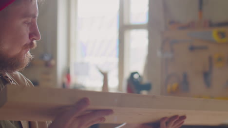 woodworker removing dust from plank