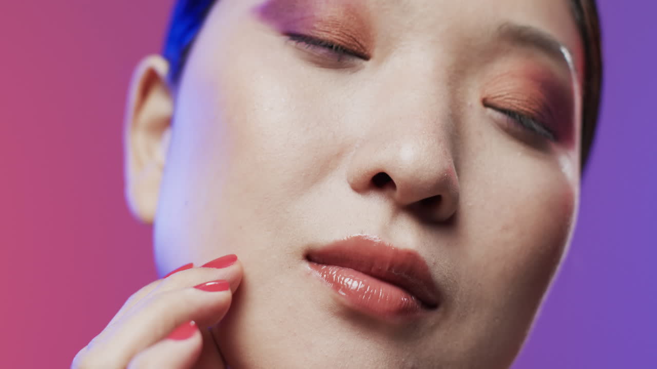 mujer asiática con cabello negro y maquillaje tocando la cara, copiar el espacio, cámara lenta