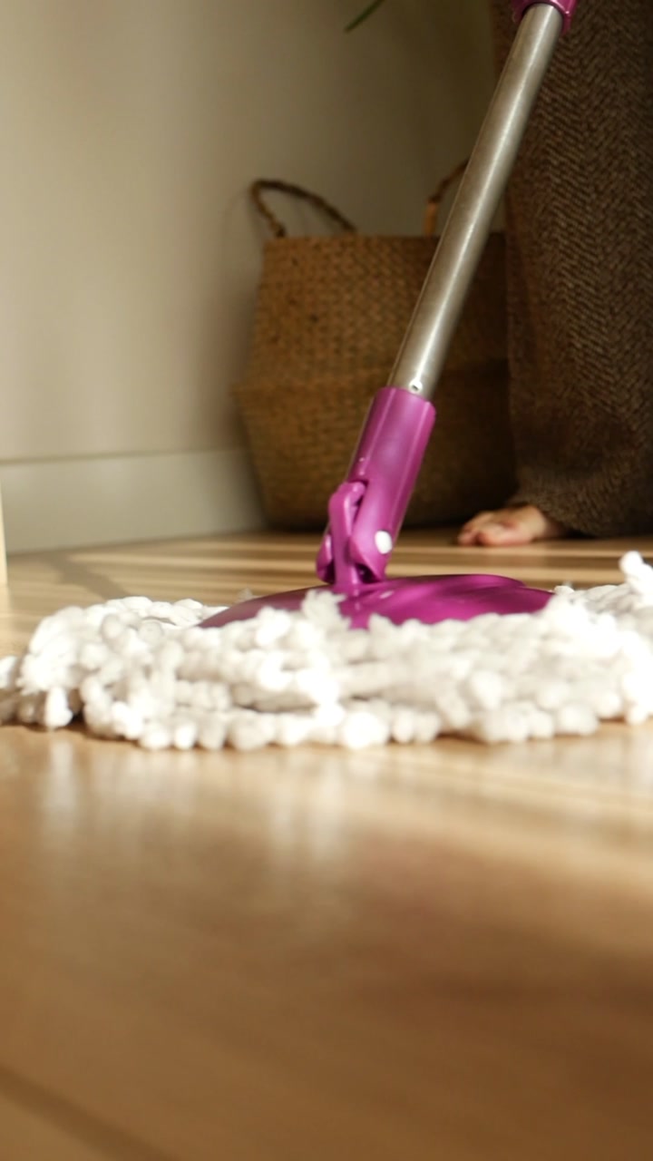 Person Mopping a Wooden Floor with Sunlight and Shadows