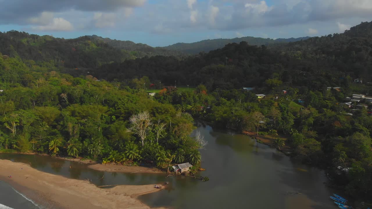 A historic house sits at the end of the river as it eventually flows into the ocean with fishing boats and kayak alongside the river on the Caribbean island of Trinidad