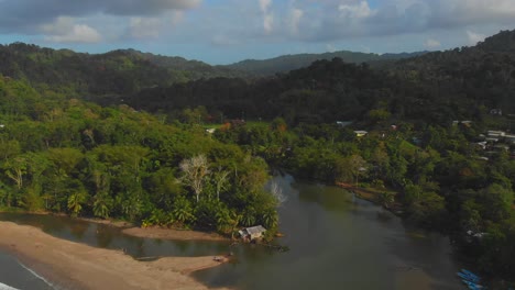 a historic house sits at the end of the river as it eventually flows into the ocean with fishing boats and kayak alongside the river on the caribbean island of trinidad