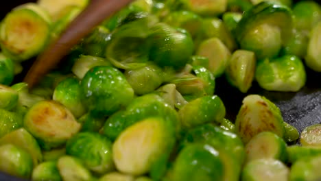 Gerösteten-Sautierten-Rosenkohl-In-Einer-Gusseisernen-Pfanne-Kochen---Rühren-Und-Mischen-Mit-Einem-Holzspatel---Weitschuss