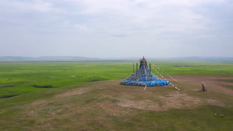 aerial orbit around ornate flags on mongolia grassland hillside, cloudy day