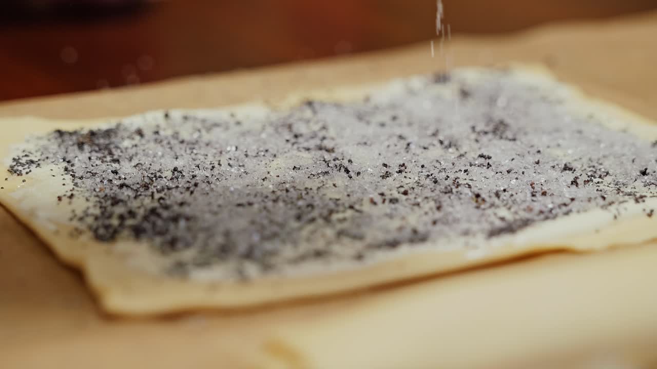 Close-up of sweet dough prep as sugar coats poppy seed filling before baking