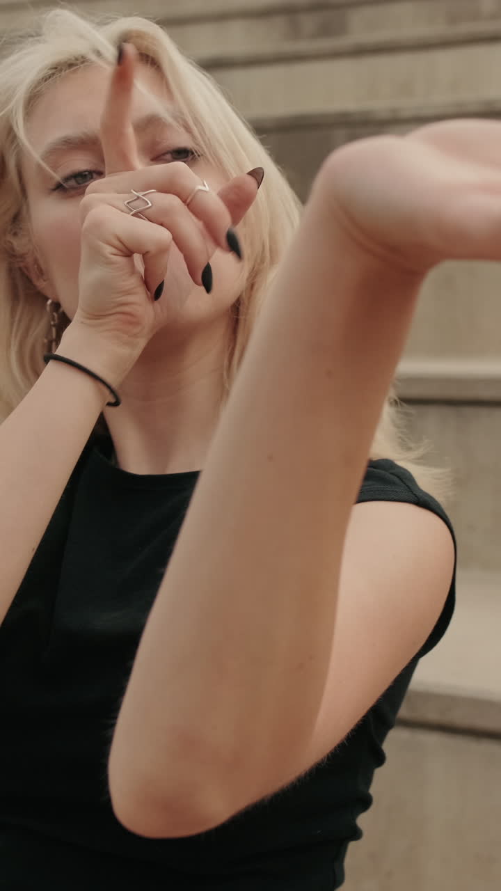 Giovane donna bionda con movimenti espressivi delle mani in posa all'aperto