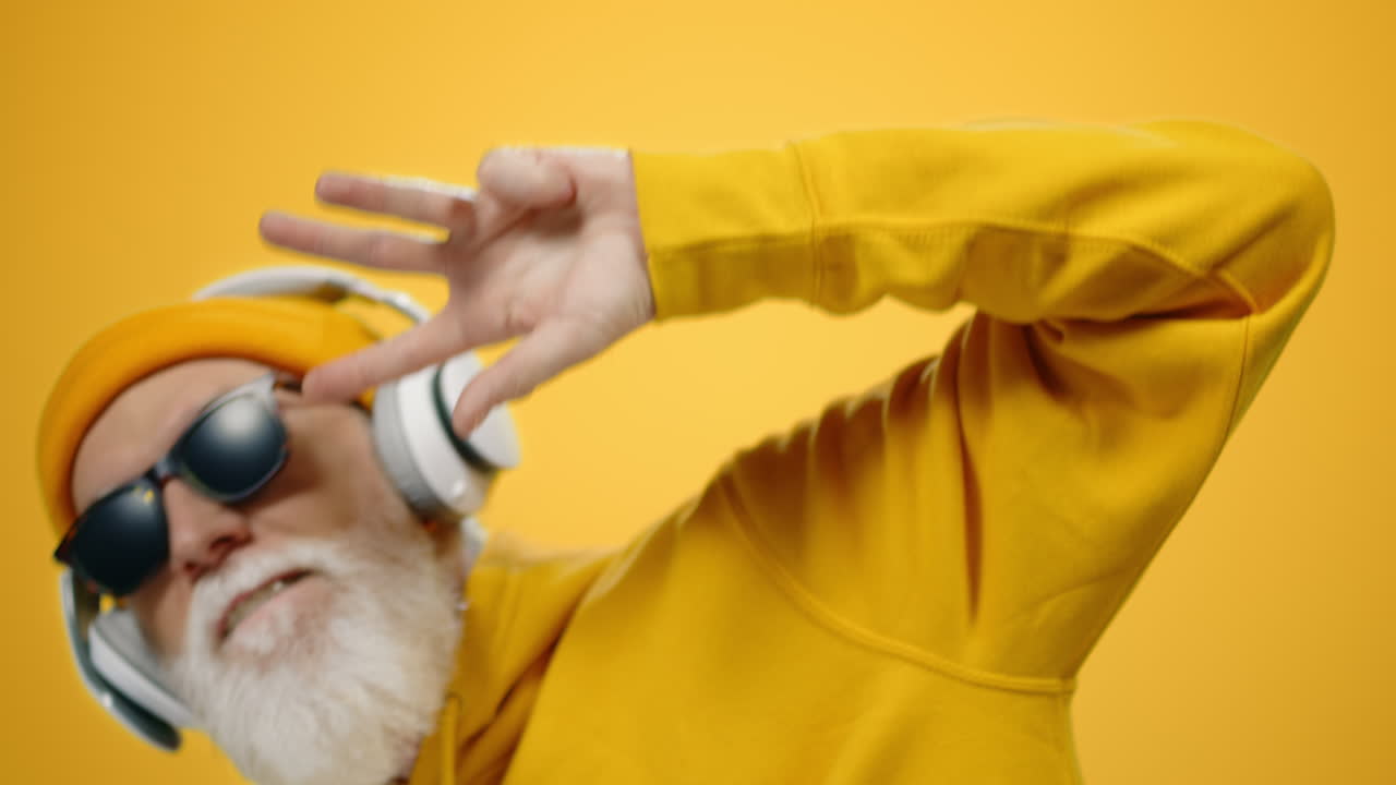 hombre sonriente relajándose en el estudio. hombre viejo escuchando música en auriculares en el interior.