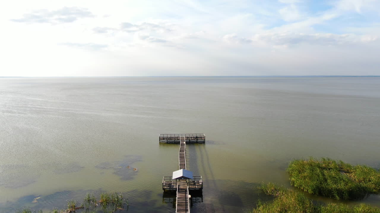 volando hacia abajo para revelar un muelle junto al lago y un parque en una tranquila tarde de primavera en florida