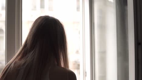 Blonde-woman-spraying-cleaning-window-with-rag-while-doing-housekeep-work-at-home