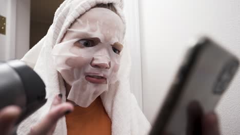 woman with face mask looking at phone in bathroom