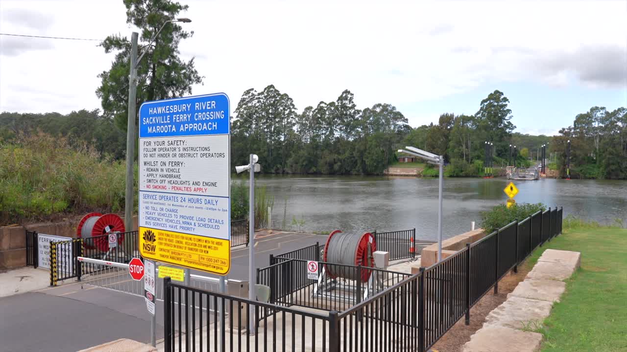 Strada che porta all'attraversamento del traghetto per veicoli di Sackville con fiume, segnaletica e rampa di carico più avanti, Australia