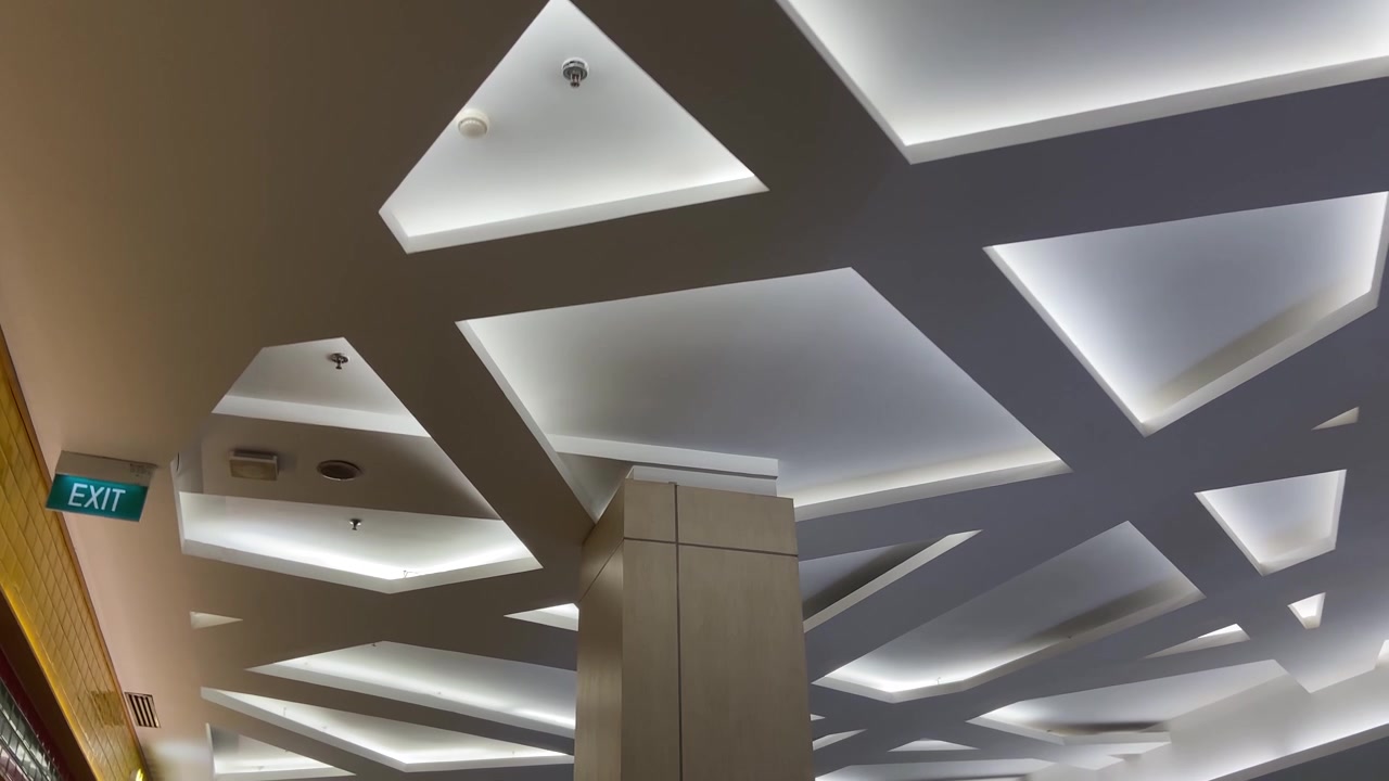Design geometrico moderno del soffitto con illuminazione brillante in un centro commerciale