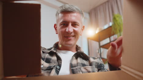 feliz hombre sonriente comprador desempaque caja de cartón entrega paquete compras en línea compra en casa
