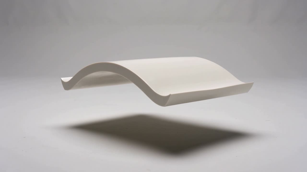 Tilting white S-shaped panel after sequence start, shadow shifting beneath backdrop