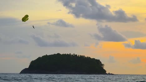 parasailing al atardecer sobre una isla tropical