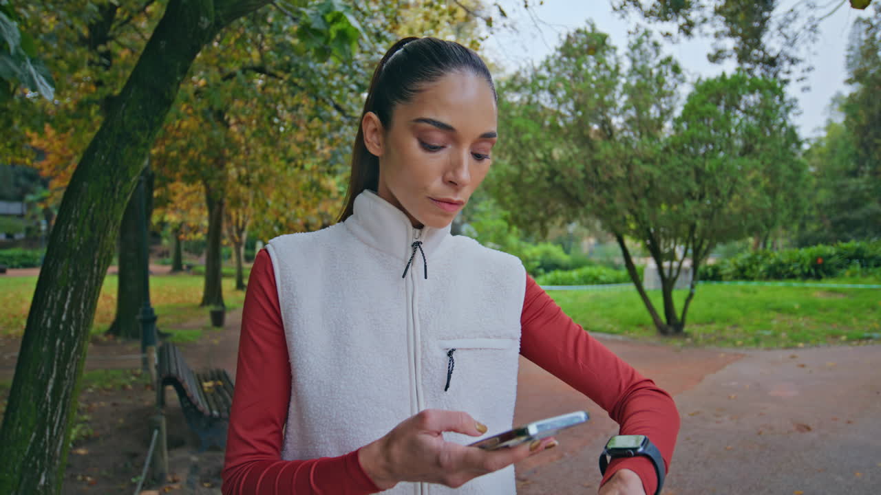 mujer deportiva comprobando el reloj inteligente en el parque verde preparándose para un primer plano de fitness