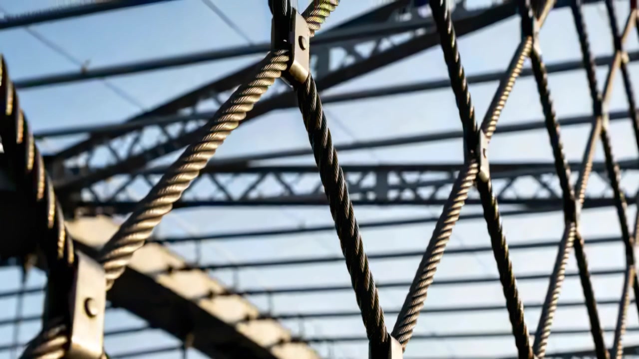 Shifting camera bringing cable mesh into sharp focus on bridge, showing clamps and truss arch