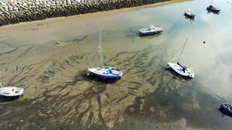 Antena-Birdseye-Por-Encima-De-Los-Barcos-En-La-Reluciente-Y-Soleada-Playa-De-Arena-Estampada-Durante-La-Marea-Baja-Marina-Slow-Dolly-Tire-Hacia-Atrás-A-La-Izquierda