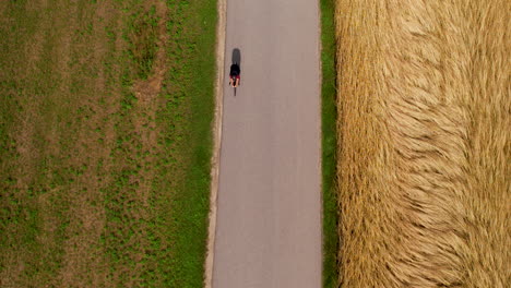 Vista-De-Arriba-Hacia-Abajo-De-La-Carrera-Ciclista-En-Un-Lugar-Rural-Con-Campos-Agrícolas-De-Trigo