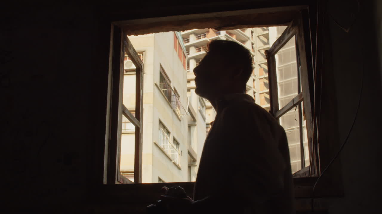 Silhouette of Man Photographing from Window inside Destroyed House