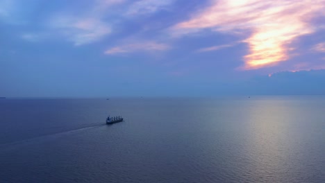 cinematic epic shot of ship sailing in sea toward sunset horizon