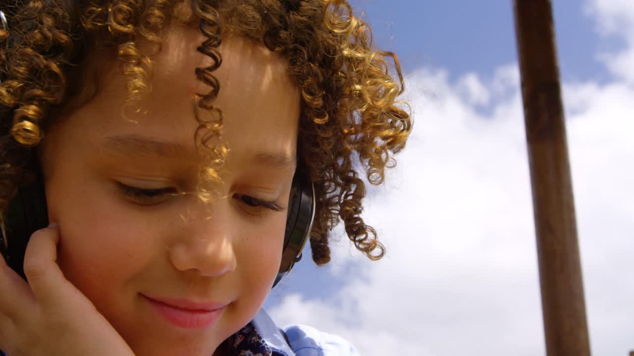 Close-up de aluna mestiça ouvindo música com fones de ouvido no pátio da escola 4k