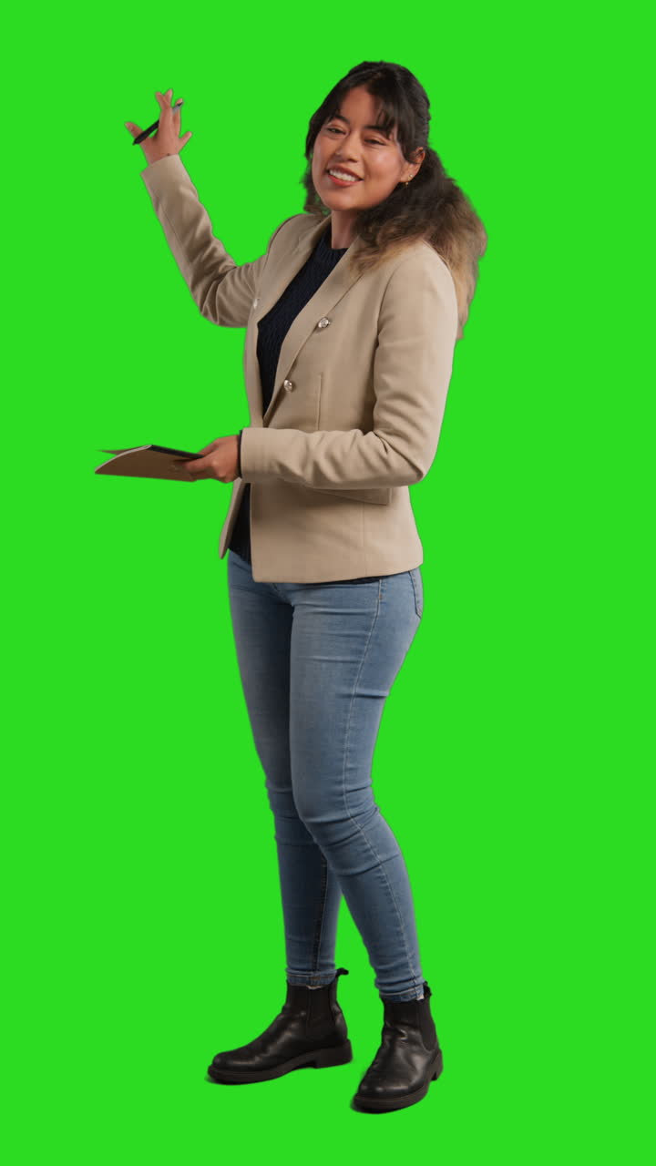 video vertical de longitud completa toma de estudio de maestra con cuaderno hablando a la clase de pie contra la pantalla verde 2