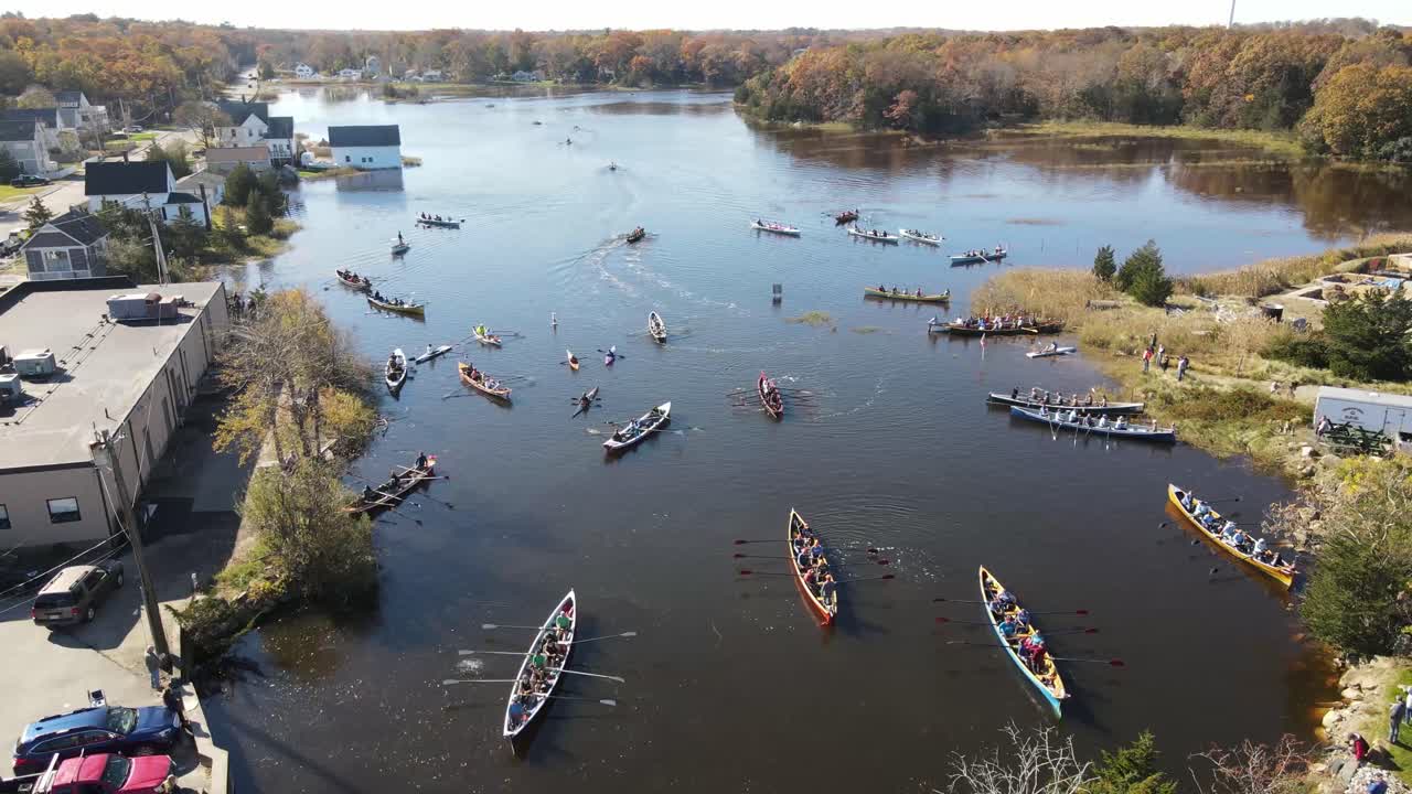 Aerial high altitude footage of teams of canoe racers waiting to start race