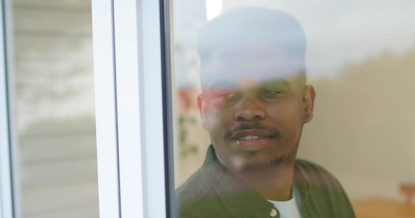 African American man responding to off-frame movement, turning head and watching through glass door