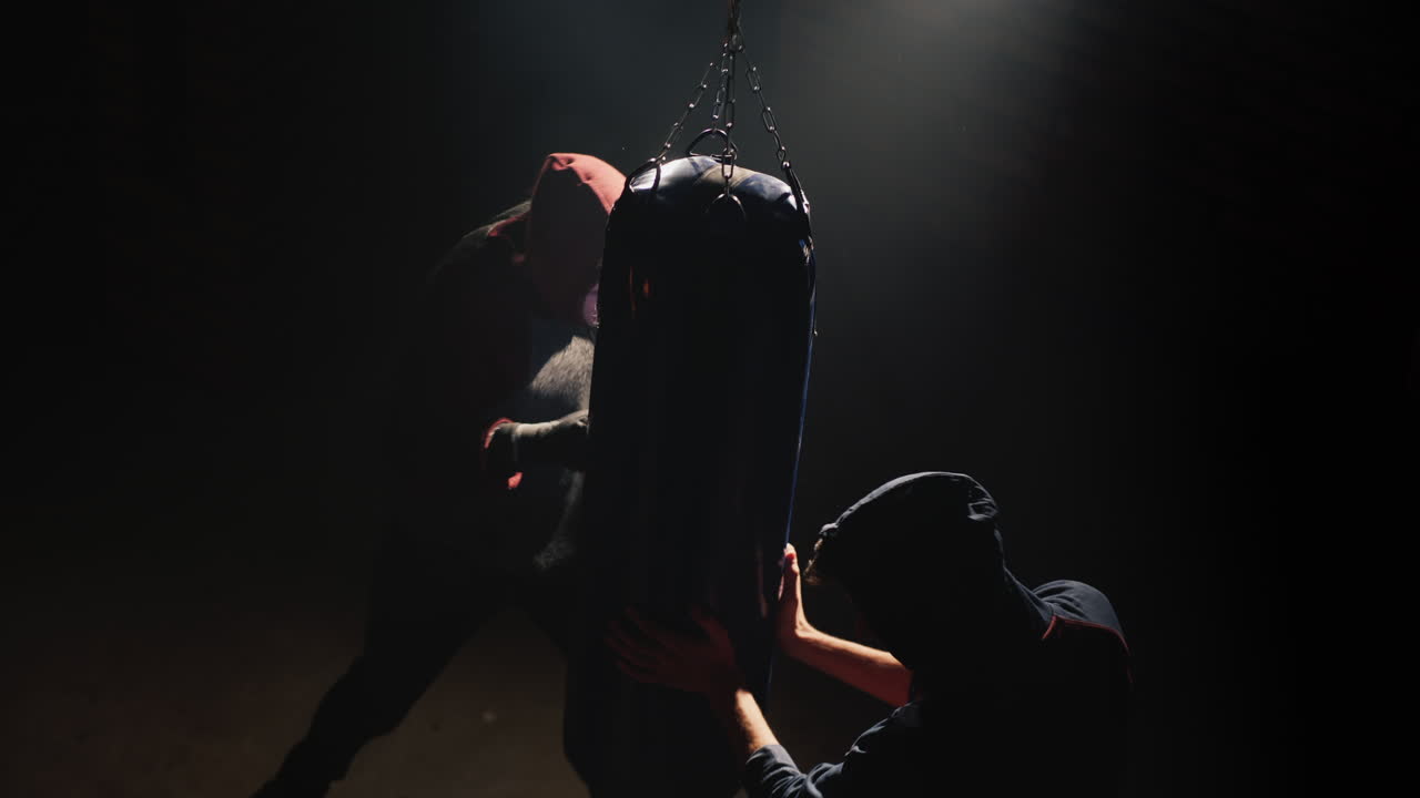 Premium stock video - Two young fighter fighters train with a punching bag