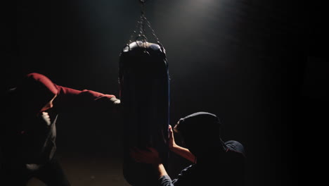 Dos-Jóvenes-Luchadores-Entrenan-Con-Un-Saco-De-Boxeo