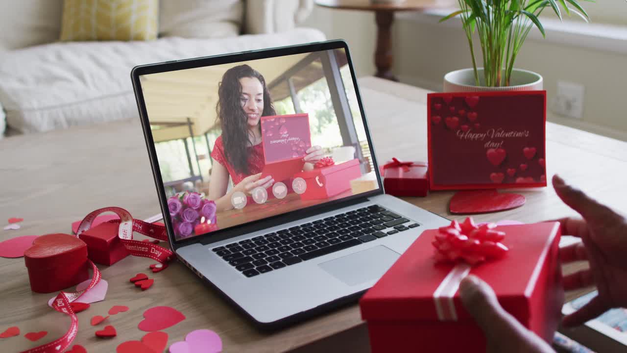 Happy biracial woman with vitiligo reading valentine card on valentine's day video call on laptop