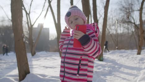 Child-girl-blogger-making-video-call-on-mobile-phone,-selfie-photo-for-social-networksin-winter-park