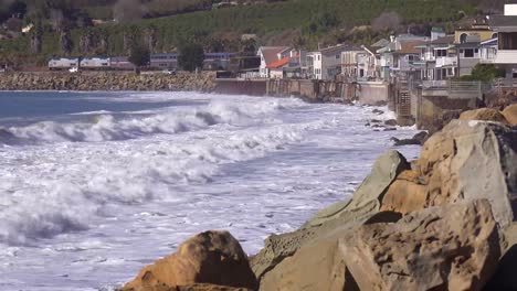 Un-Tren-De-Pasajeros-De-Amtrak-Pasa-Cuando-Las-Olas-Y-Las-Olas-Chocan-Contra-Las-Casas-De-Playa-Del-Sur-De-California-Durante-Una-Tormenta-Muy-Grande