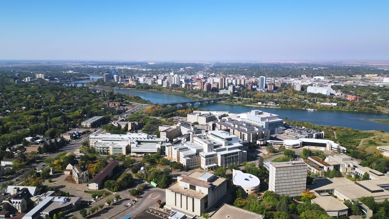 Langsomt fremadgående luftoptagelse over Saskatoon campus om efteråret, downtown skyline, blå himmel
